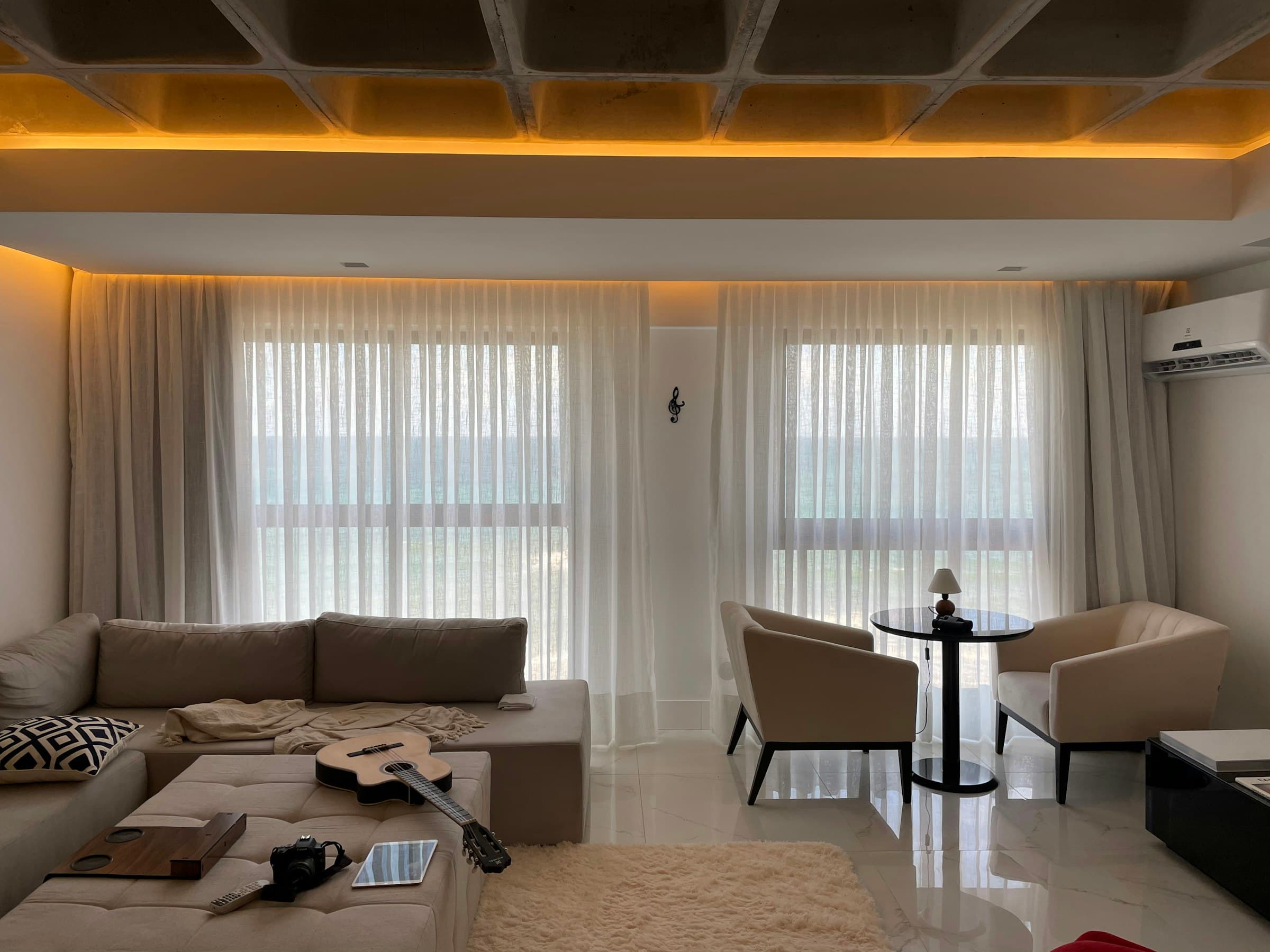 Sala con visillos de piso a techo cubriendo todo el ventanal