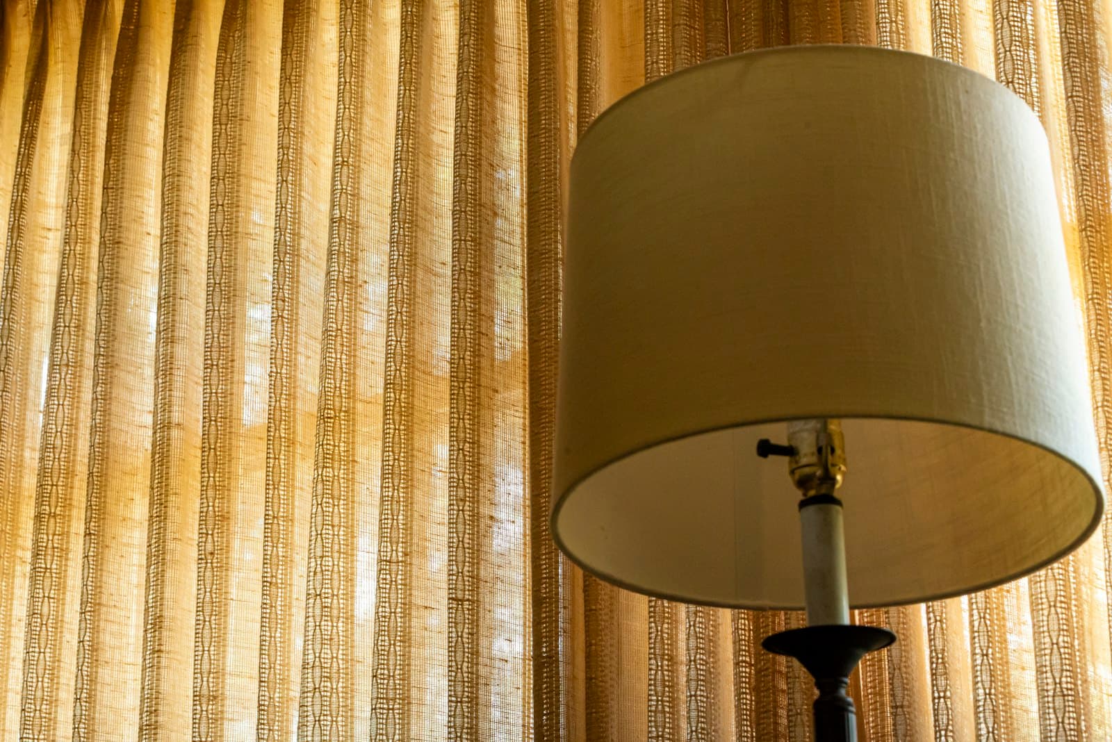 Visillo dorado filtrando la luz junto a una lámpara (foto de referencia, reemplazar por foto propia)